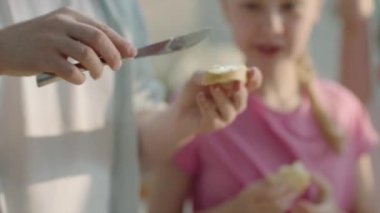 Babanın yağlı ekmeğini peynirle kaplamasını, çocukların meyve suyu içmesini, kruvasan yemesini. Yüksek kalite 4K görüntü. Panorama çekimi