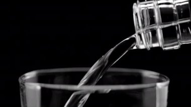 Siyah arkaplandaki bardağa durgun su dökülüyor. Yüksek kalite 4k görüntü