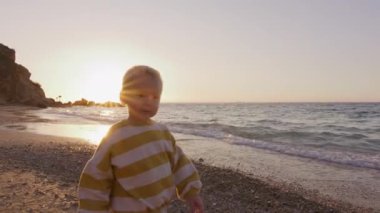 Gün batımında kumsalda taş atan sevimli küçük çocuk. Yüksek kalite 4k görüntü