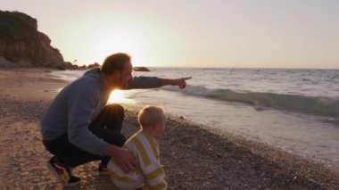 Baba ve oğul sahilde günbatımının tadını çıkarıyorlar. Yüksek kalite 4k görüntü