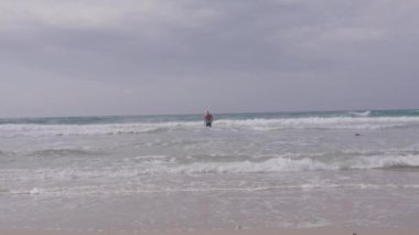 Kıdemli adam okyanusta yüzecek. Suyu takip eden mayo giyen birinin arka planı.