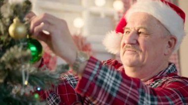 Son sınıf öğrencisi Noel Baba şapkası takıyor, evde Noel ağacı süslüyor. Yüksek kalite 4k görüntü