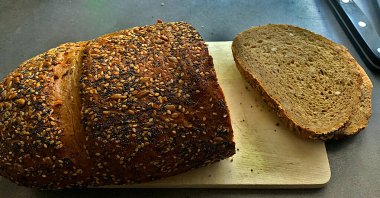 Tahta zemin üzerinde bıçak olan taze ekmek.