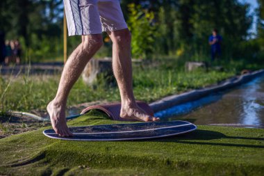 Yazın sığ sularda kaykay yapan genç bir adam aktif yaşam tarzının ve güneşli havanın tadını çıkarıyor. Açık hava aşırı su sporları aktivitesi.
