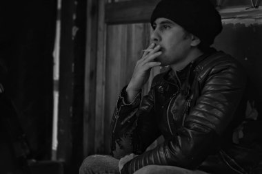Sigara içen genç bir adam. Üzgün suratlı bir adam, sigara bağımlısı..
