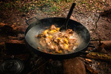 Ateşin üzerinde büyük bir paella tavası. Büyük demir disk benzeri tencere, doğada yemek pişirme..