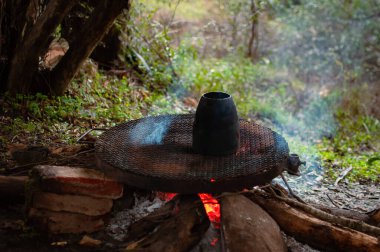 Kamp ateşinin üzerinde ısınan su. Dışarıdaki odun ateşinin üzerinde çelik bir sürahi kaynar su..