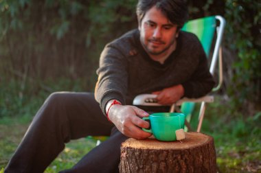 Bahçede oturan ve içen adam. Doğa, sıcak içecek..