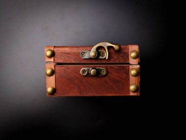 A locked mysterious wooden chest is on a black background.