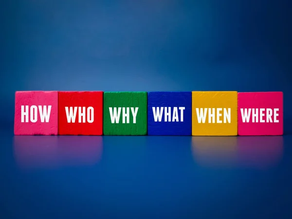 Colored cube with the word WHERE,WHO,WHAT,WHEN,WHY and HOW on blue background.