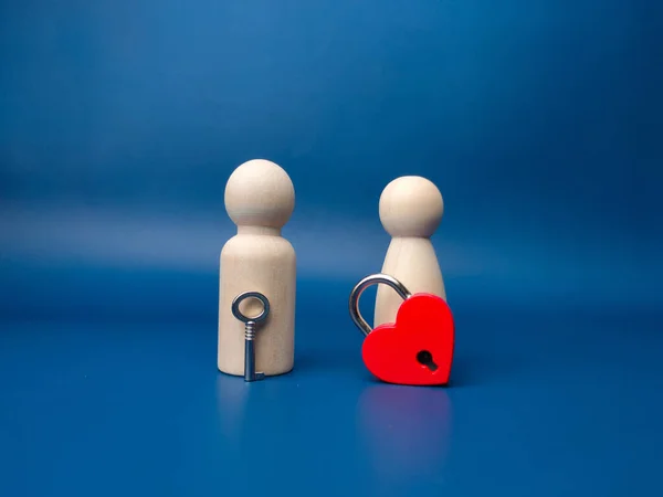 Couple wooden peg doll with love padlock and key on a blue background.