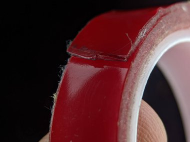 Close-up red double sided adhesive tape on a black background.