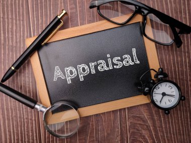 Magnifying glass and alarm clock with the word Appraisal on a wooden background.