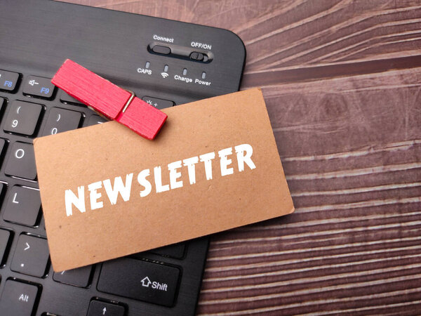 Card board with the word NEWSLETTER on wooden background.