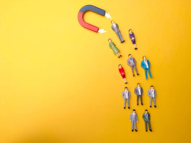 İş adamı sarı arka plandaki mıknatıs tarafından çekiliyor. İş ve liderlik kavramı.