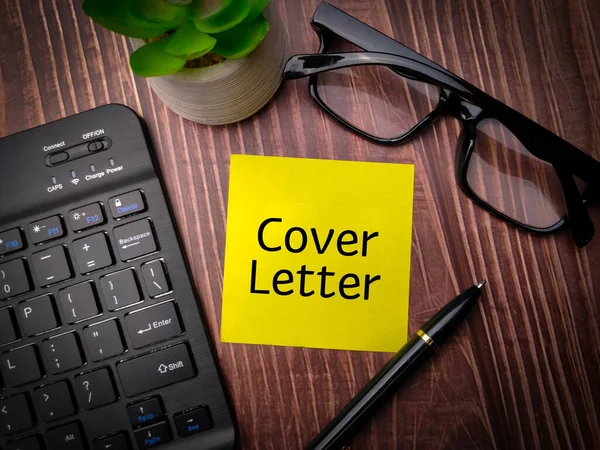 Keyboard,pen and glasses with the word Cover Letter on wooden table background.