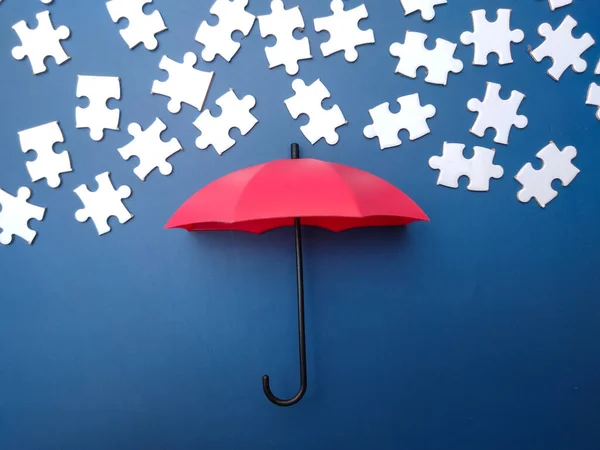 Red umbrella with white puzzle on a blue background.