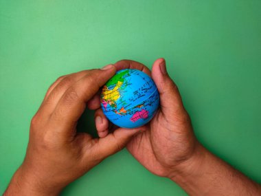 Hand holding earth globe on a green background.Nature and earth concept.