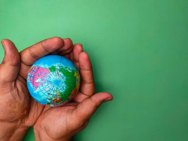 Hand holding earth globe on a green background.Nature and earth concept.