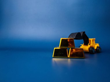 Mavi arka planda kazıcı ve altın külçesi. İş konsepti.