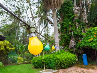 Bir tatil köyünün bahçesinde asılı duran sarı ampul..