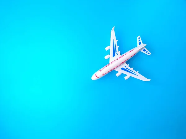 Top view white toy airplane on a blue background with copy space.