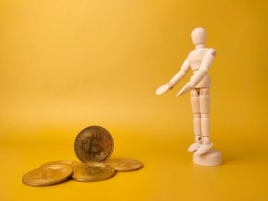 Ahşap manken ve sarı arka planda bitcoinler..