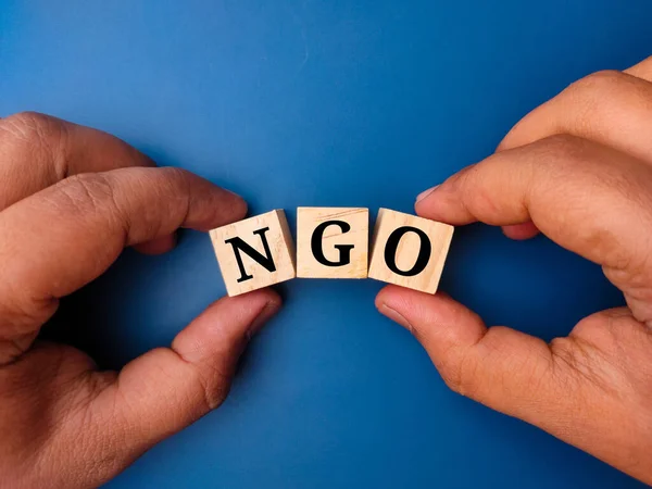Hand Hält Farbigen Würfel Mit Dem Wort Ngo Auf Blauem — Stockfoto