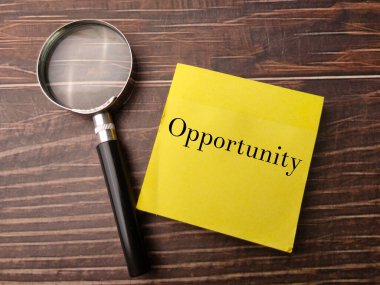 Ahşap zemin üzerinde Opportunity yazan bir büyüteç ve yapışkan not. İş konsepti.