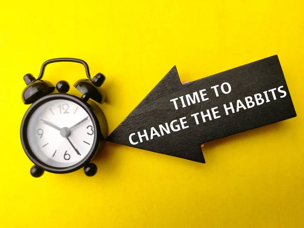 stock image Alarm clock and wooden arrow with text TIME TO CHANGE THE HABBITS on yellow background