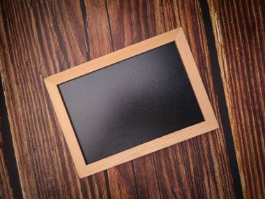 Üst görünüm, tahta zeminde düz siyah bir karatahta..