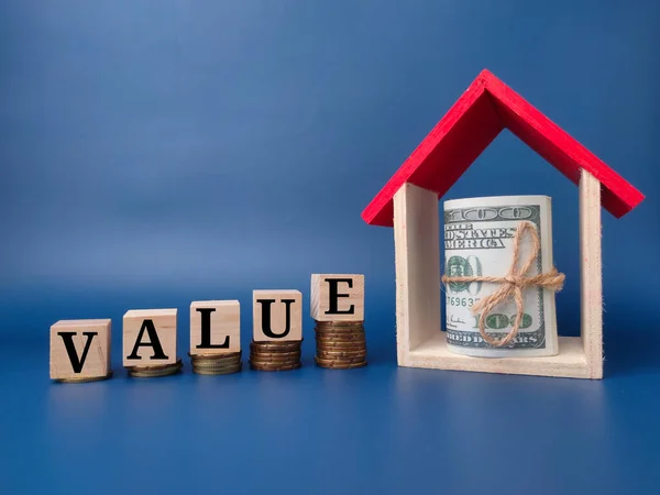 stock image Toy house and banknote with the word VALUE on a blue background.