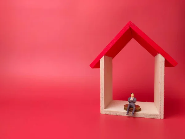 Toy house with miniature people on a red background. Business concept.