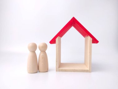 Ahşap bebek figürleri ve beyaz arka planda oyuncak ev.