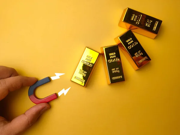 手押し磁石は黄色の背景に金の棒を引き付ける — ストック写真