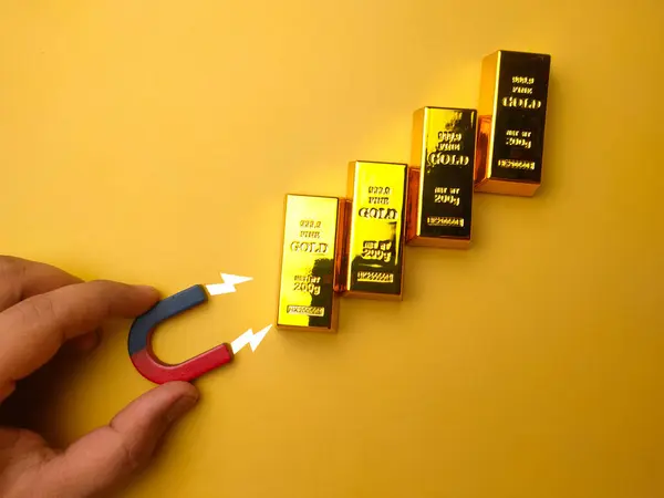 Mão Segurando Ímã Atrair Barra Ouro Fundo Amarelo — Fotografia de Stock