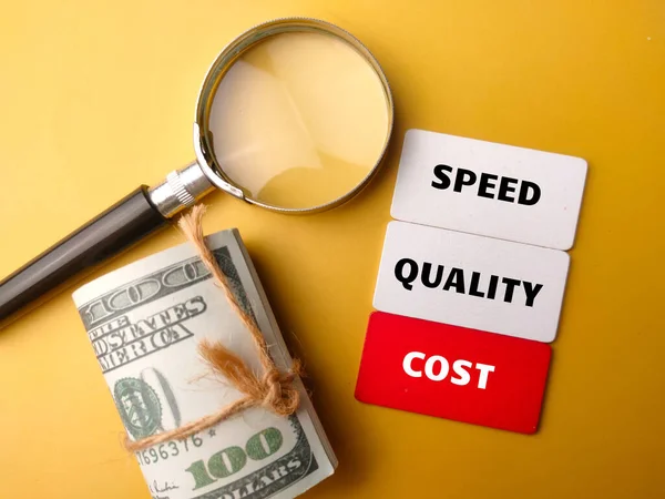 黄色背景上印有 Speed Qality Cost 字样的顶部视图钞票和放大镜 — 图库照片