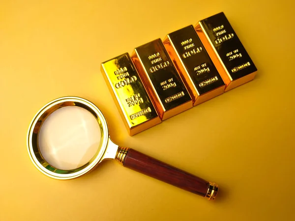 Vintage magnifying glass and gold bar on a yellow background.