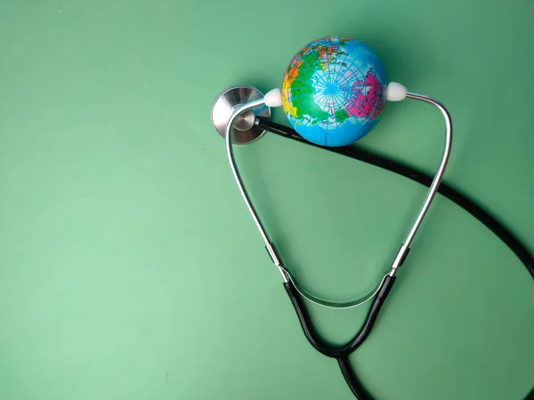 stock image Stethoscope and earth globe on a green background. Healthcare and medical concept.