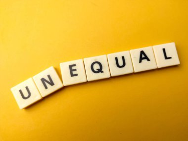 Sarı arka planda UNEQUAL sözcüğüyle oyuncak kelime