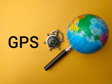 Üst görünüm pusulası, büyüteç ve GPS (Küresel Konumlandırma Sistemi) sözcüğüyle yer küresi)