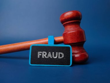 Gavel and wooden board with the word FRAUD on a blue background. clipart