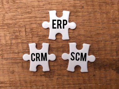 Top view white puzzle with the word ERP CRM SCM on a wooden background. clipart