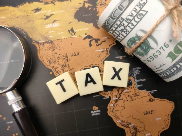在世界地图背景上用Tax这个词放大玻璃和钞票 — 图库照片