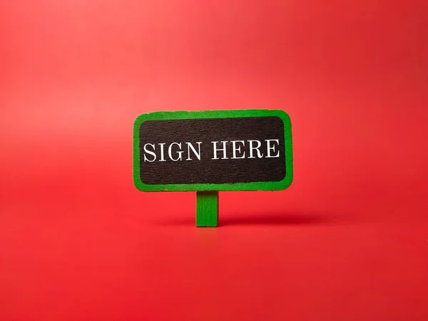 赤い背景に Sign Here の文字が入ったカラー看板 — ストック写真