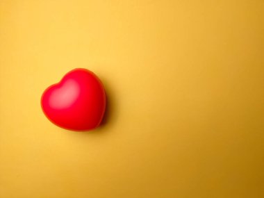 Sarı arkaplanda kırmızı kalp şekli ve fotokopi alanı. Kalp kontrolü ya da aşk konsepti için kullanılabilir