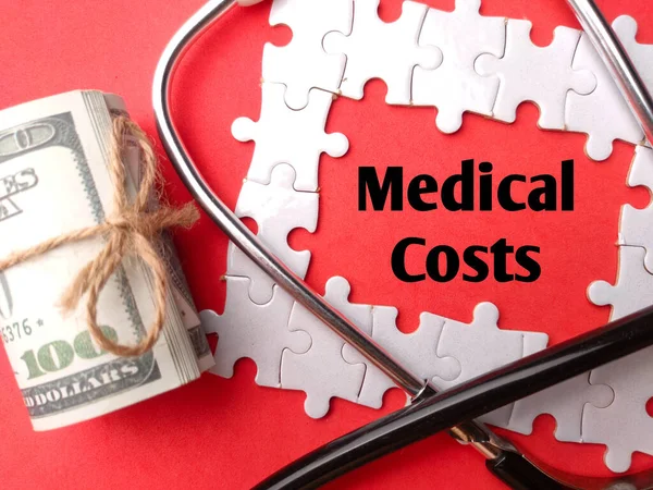 Stethoscope and banknotes with the word Medical Costs on a red background. Healthcare and medical concept.