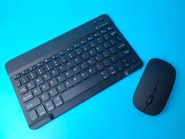 stock image Malaysia,30 April 2022: Black Bluetooth wireless keyboard and wireless mouse on a blue background.