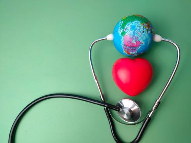 Stetoskop, toprak küre ve yeşil arka planda kırmızı kalp. Sağlık ve Tıp Konsepti.