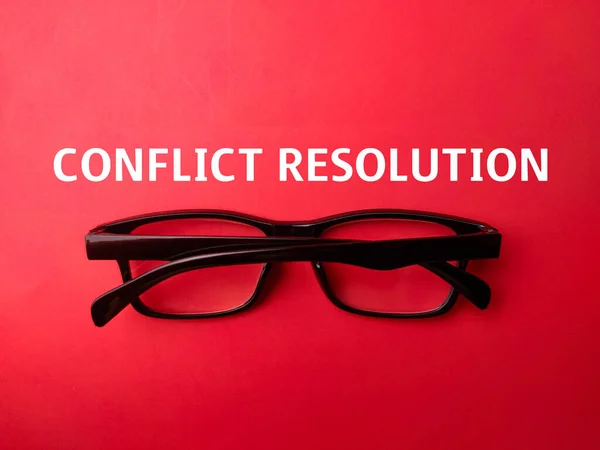 Black glasses with the word CONFLICT RESOLUTION on a red background